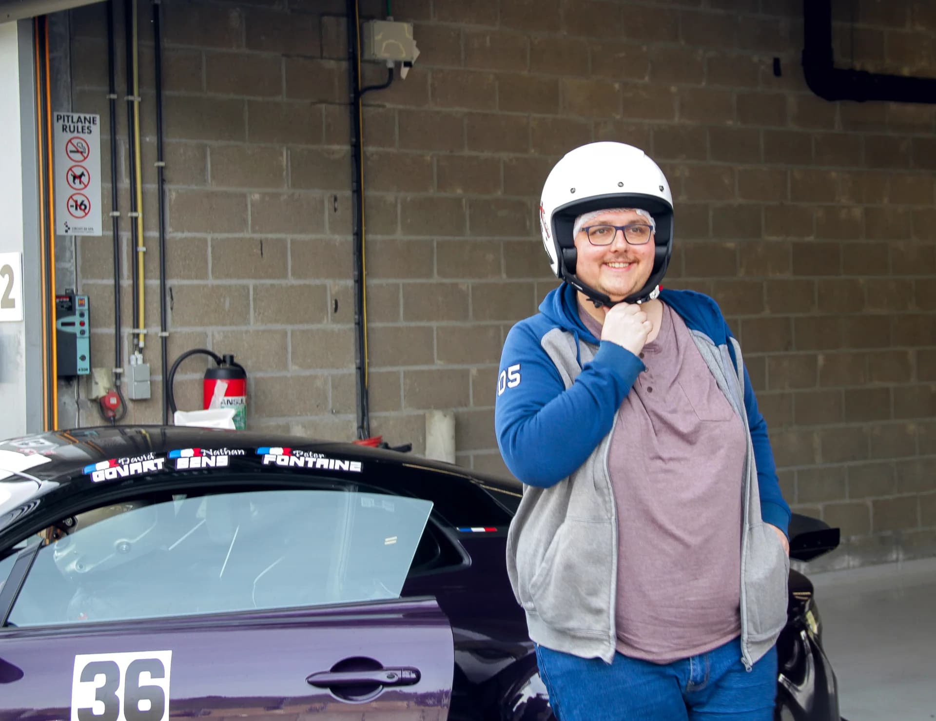 Participant casqué près de la voiture avant une session de pilotage